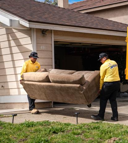 Crisan crew carrying an old sofa out of a San Diego garage